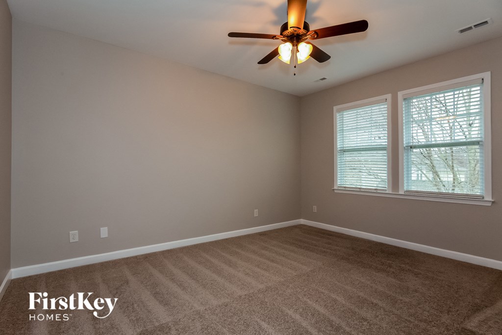 the master bedroom has a carpeted floor and a ceiling fan