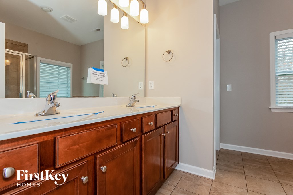 the master bathroom has two sinks and a large mirror