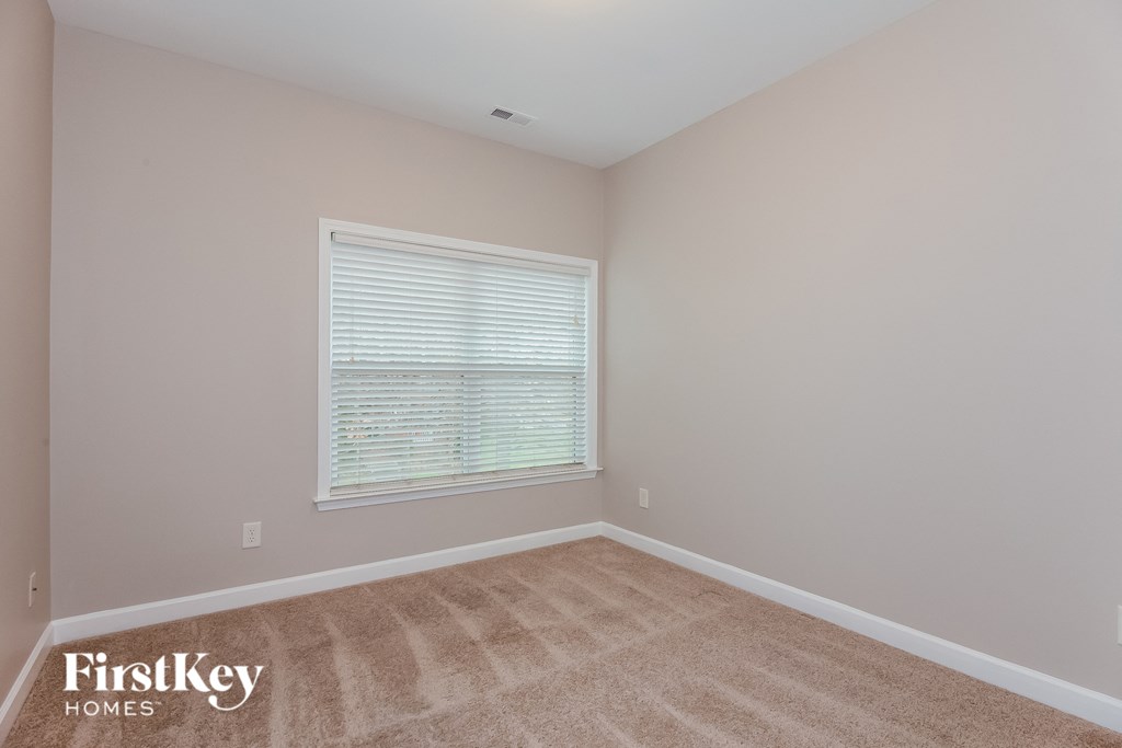 the second bedroom with a large window and beige carpeting