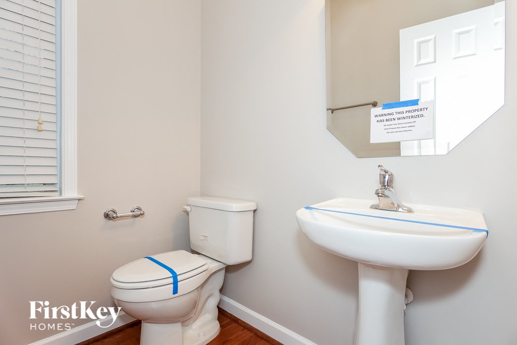 a bathroom with a toilet sink and mirror and a window