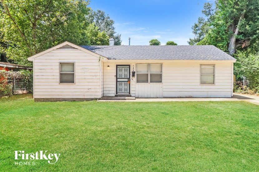 A small house with a black door and a window is surrounded by a grassy lawn.