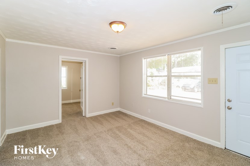 A room with a carpeted floor and a window with blinds.