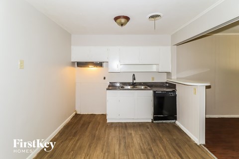 A kitchen with a black dishwasher and a black fridge under a white cabinet.