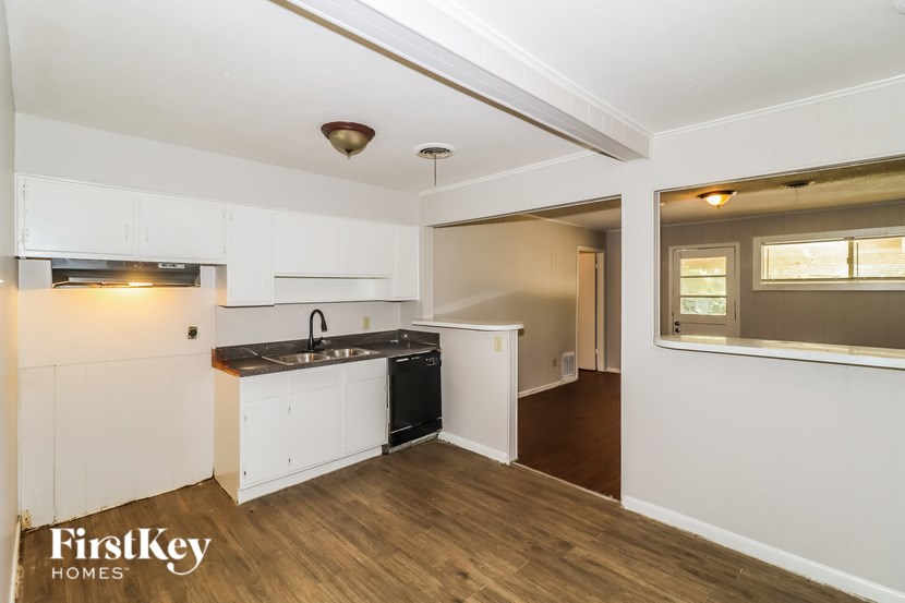 A kitchen with white cabinets and a black dishwasher.