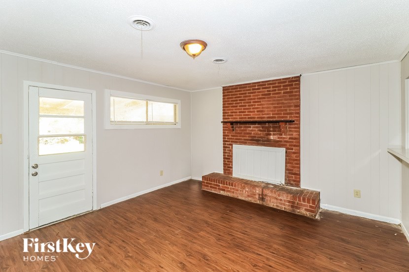 A room with a brick fireplace and wooden floors.