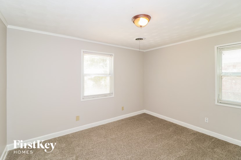 A room with a carpet floor, a window, and a light fixture.