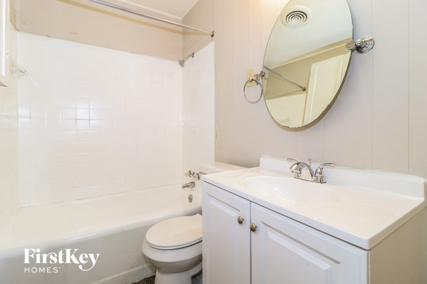 A white bathroom with a toilet, sink and mirror.