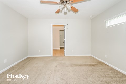 A spacious room with a carpeted floor and a ceiling fan.