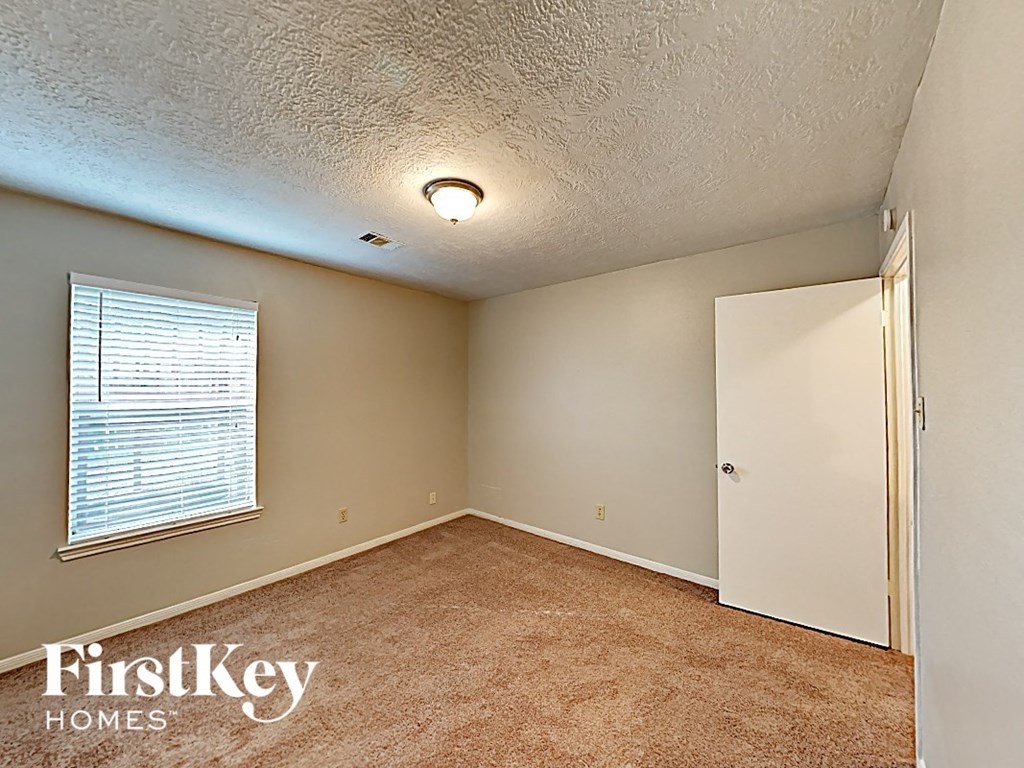 an empty bedroom with a window and a door to a closet