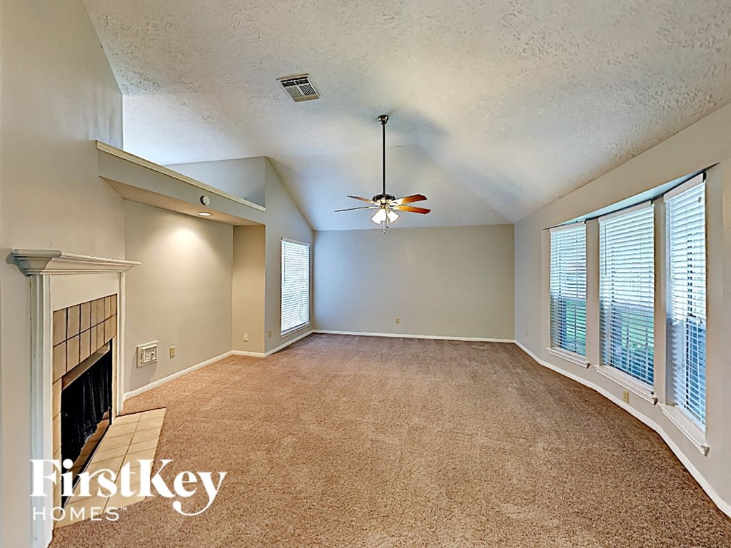 an empty living room with a fireplace and a ceiling fan