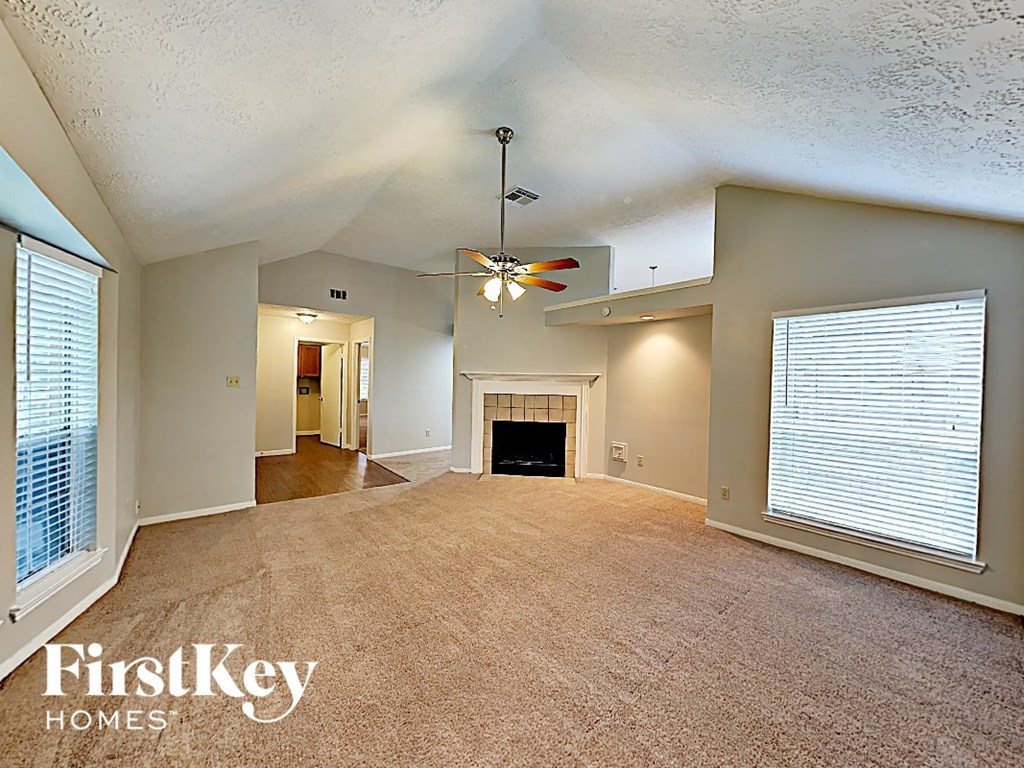 an empty living room with a fireplace and a ceiling fan