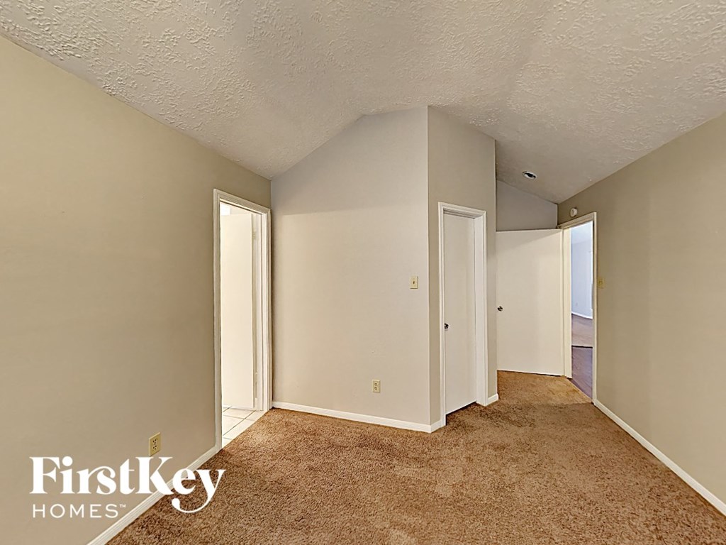 a bedroom with a carpeted floor and a door to a hallway