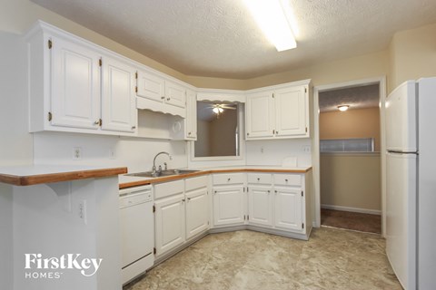 A kitchen with white cabinets and a wooden counter top.