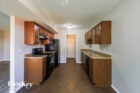 A kitchen with wooden cabinets and a black fridge.