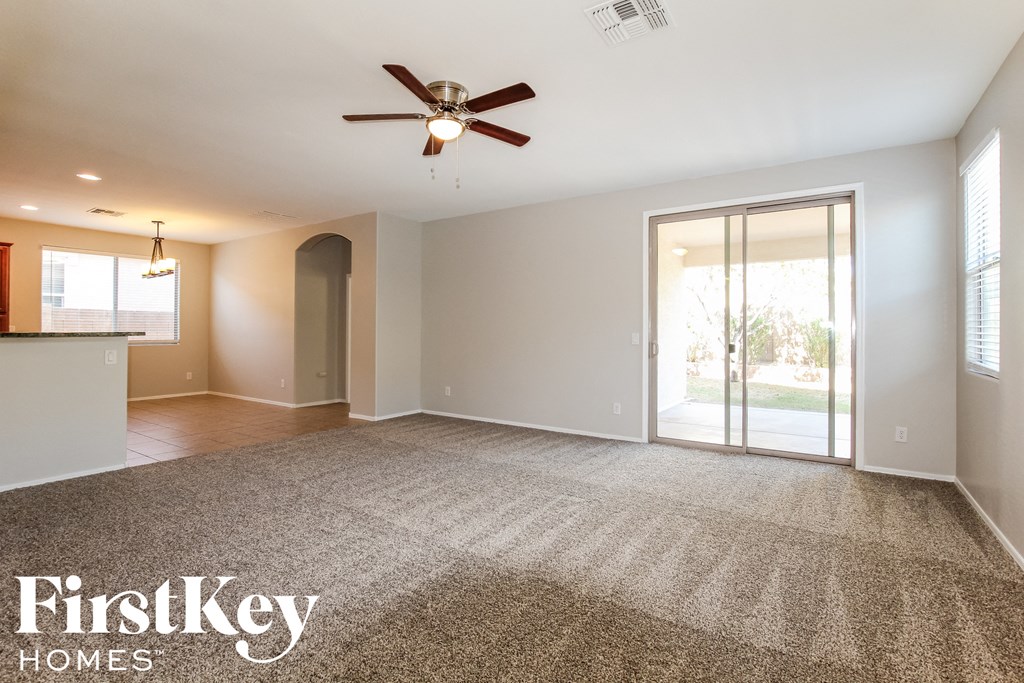 an empty living room with a ceiling fan