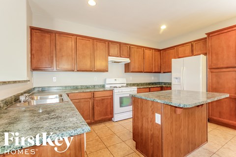 a kitchen with wooden cabinets and granite counter tops and white appliances