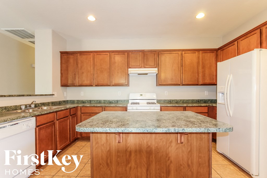 a kitchen with wood cabinets and granite counter tops and white appliances