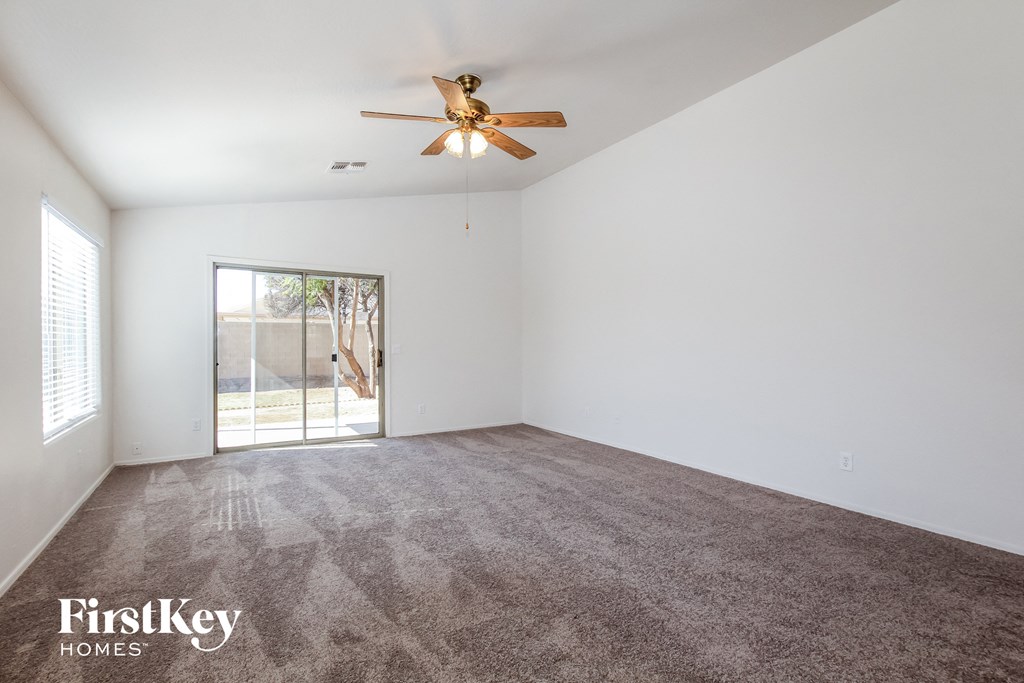 A room with a ceiling fan and a sliding glass door leading outside.