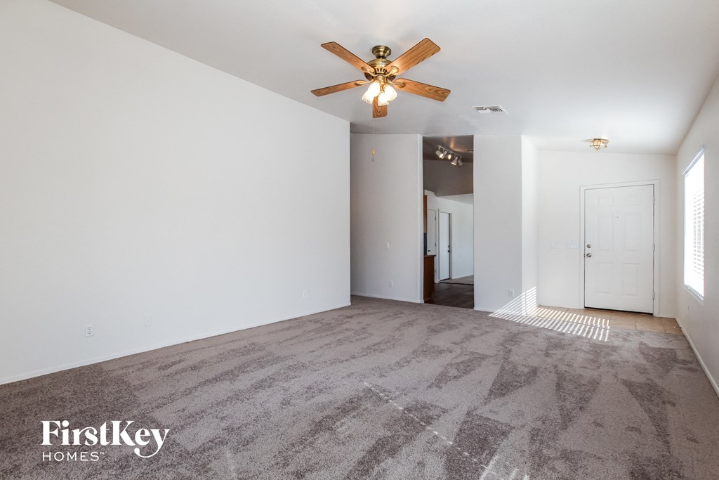 A spacious room with a ceiling fan and carpeted floor.