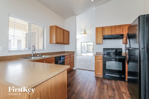A kitchen with wooden cabinets and a black fridge.