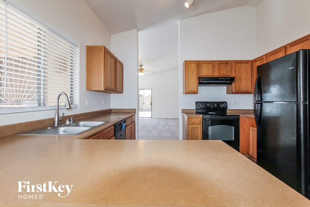 A kitchen with a black fridge and wooden cabinets.