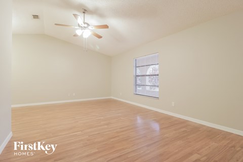 A room with a ceiling fan and wooden flooring.
