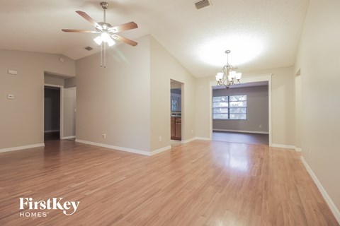 A spacious room with wooden flooring and a ceiling fan.