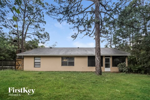 A house with a brown roof and a white door is surrounded by trees.