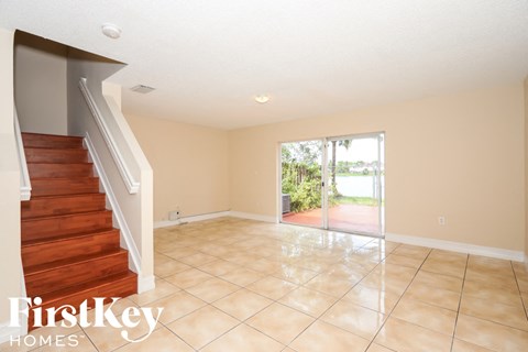 A spacious room with a staircase and sliding glass doors leading to a patio.