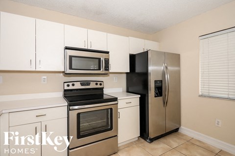 A kitchen with a stainless steel refrigerator and a black stove top oven.