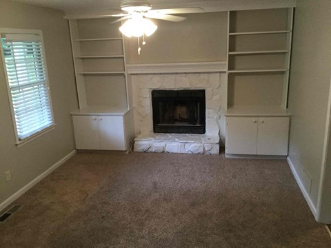 A living room with a fireplace and built-in shelves.