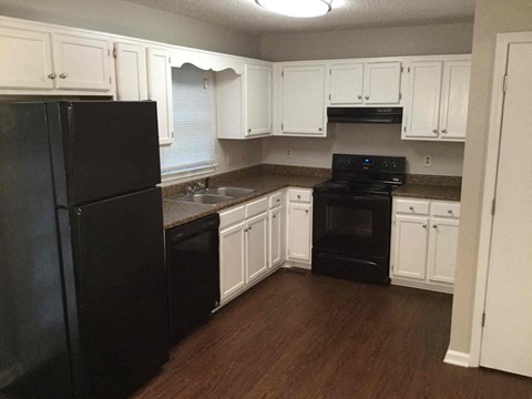 A kitchen with black appliances and white cabinets.