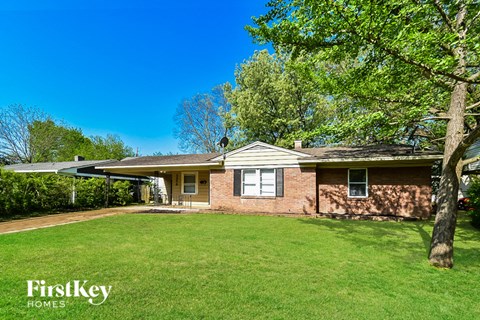 a small brick house with a yard and a tree
