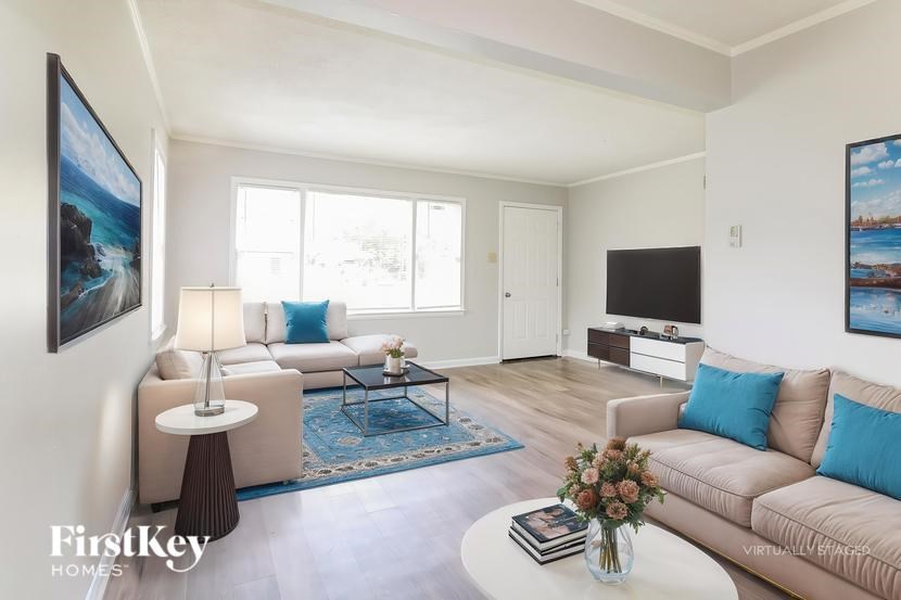 A living room with a couch, a coffee table, and a painting on the wall.