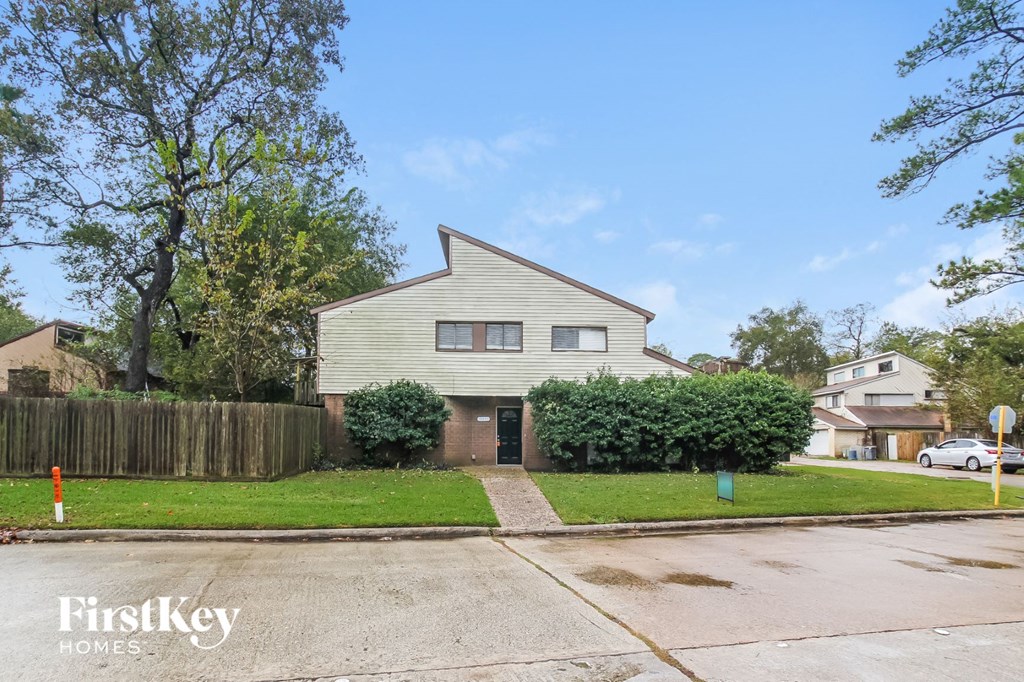 A house with a grey facade is situated on a street with a FirstKey Homes sign.