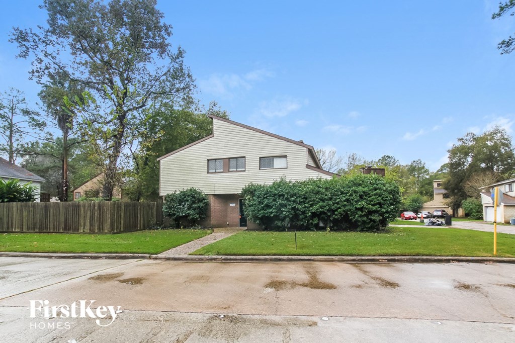 A house with a fence and a tree in front of it.