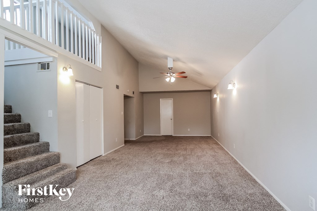A spacious room with a staircase and a carpeted floor.