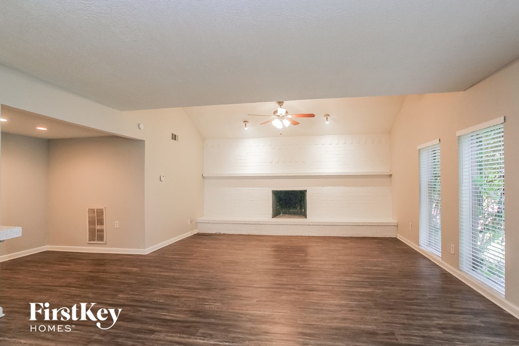 A spacious room with a fireplace and wood flooring.