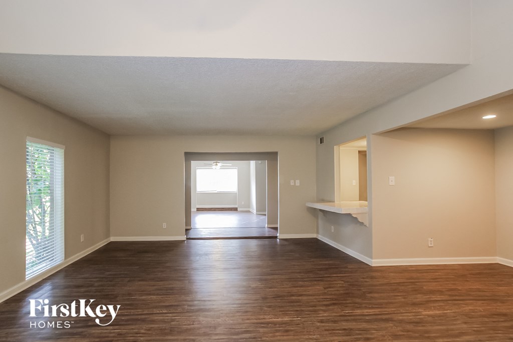 A spacious room with wooden floors and a large window.