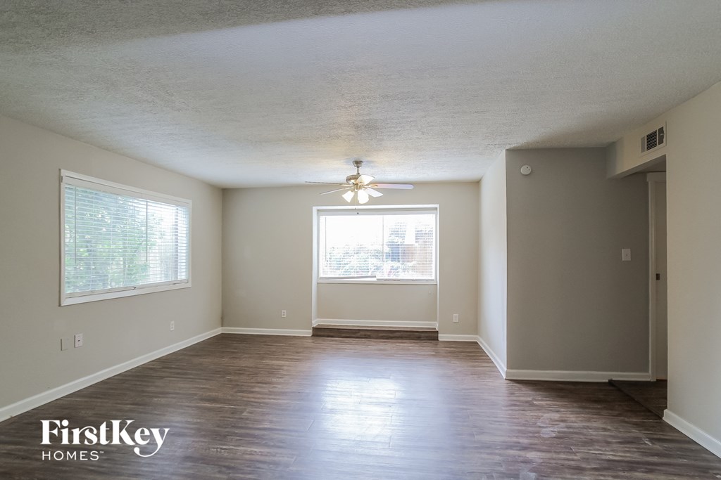 A room with wooden floors and a window with blinds.