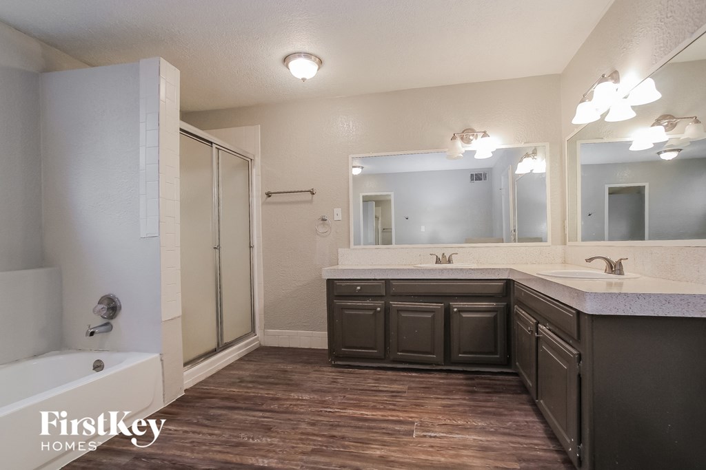 A bathroom with a wooden floor and a white tub.