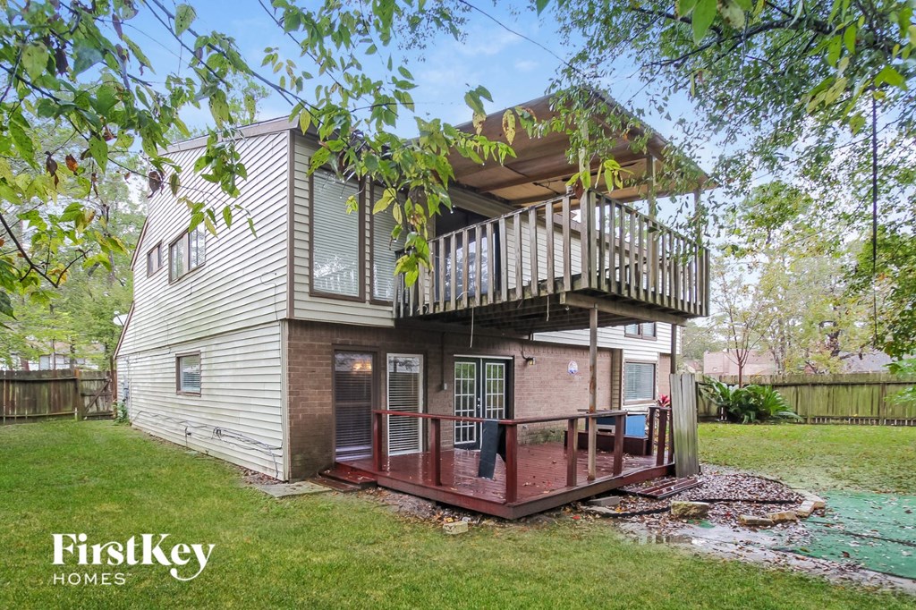 A house with a deck and a tree in front of it.