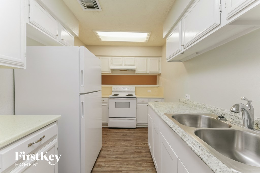 a kitchen with white cabinets and a sink and a refrigerator