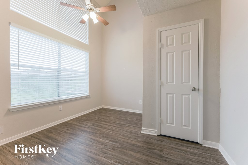 an empty room with a white door and a ceiling fan