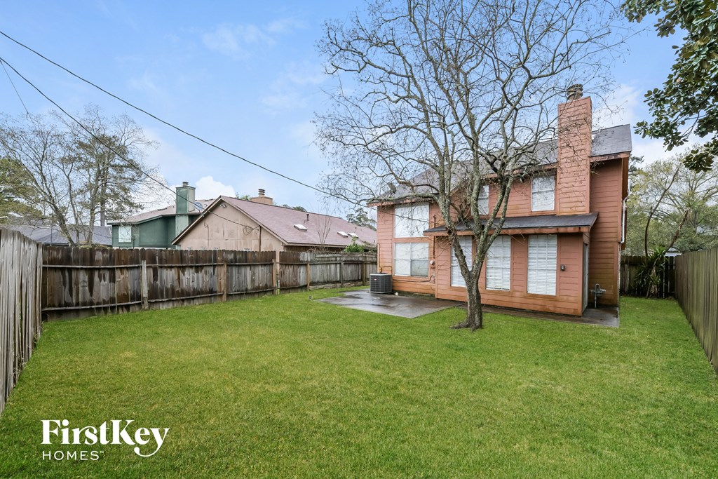 a backyard with a house and a fence and a tree