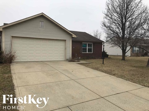 A house with a garage door and a tree in front of it.