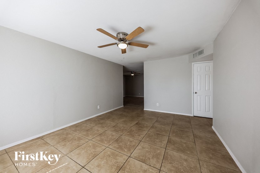 a living room with a ceiling fan and a tiled floor