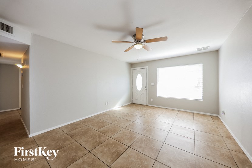 the living room has tile flooring and a ceiling fan