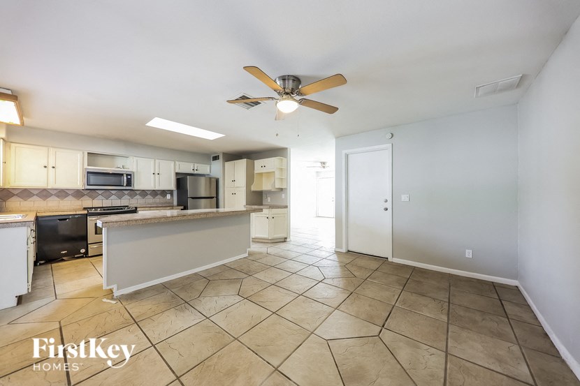 a kitchen with tile flooring and a ceiling fan