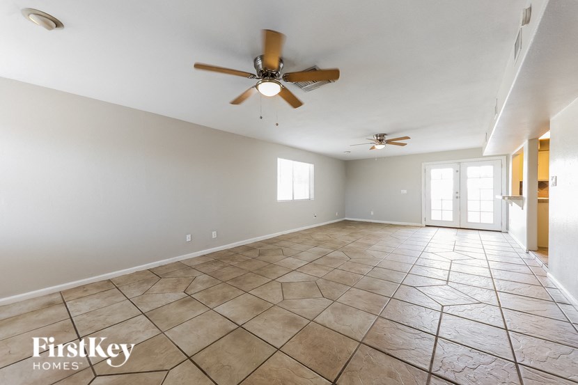 an empty living room with a ceiling fan and tiled floors